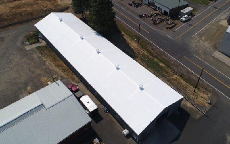 An aerial view of a commercial building with a white roof.
