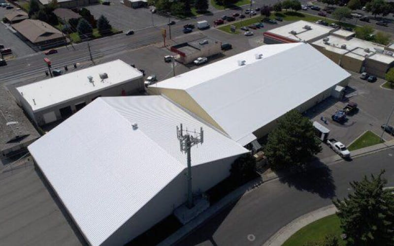 An aerial view of a building with a white commercial roof.