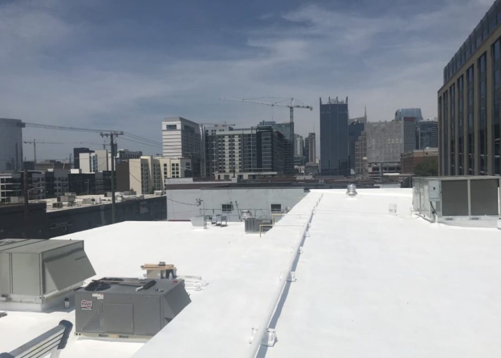A white commercial roof with a city in the background.