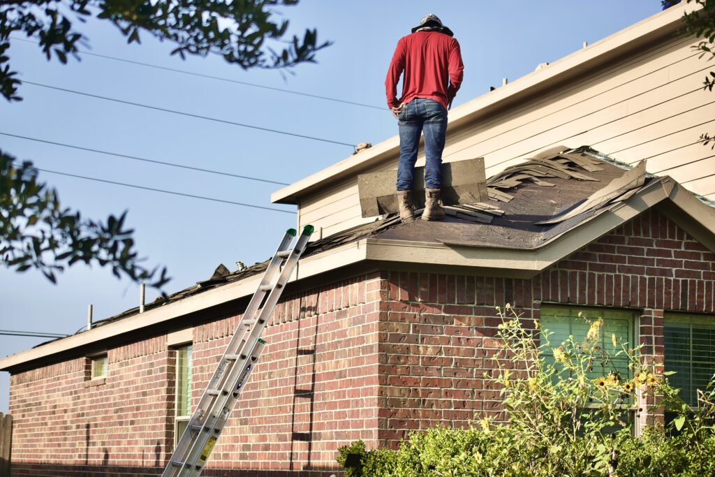 Roofer standing on a house roof during tear-off, before new underlayment is installed